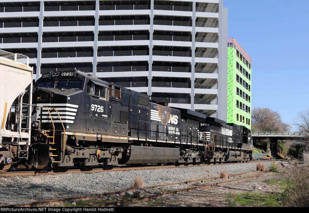 NS 9464 & 9726 lead train E25 past new construction in downtown